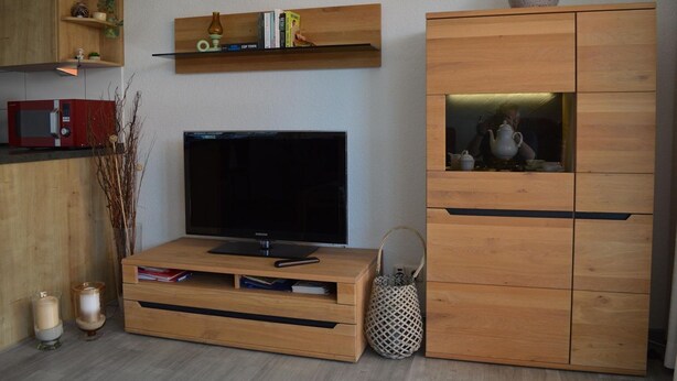 A modern living room with a flat-screen TV, wooden cabinets, and shelves with books and decorative items. - Ferienwohnung Wohnpark Warfstr. 5/4 - Wohnpark Werdum (Werdum)
