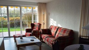 A living room with a plaid sofa, armchairs, a coffee table, and a lamp. - Ferienwohnung Wohnpark Warfstr. 5/4 - Wohnpark Werdum (Werdum)