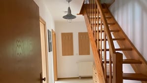 A hallway with a wooden staircase, a ceiling light, and two wooden panels on the wall. - Ferienwohnung Am Harlebogen 10 Whg. 4 (Wittmund)