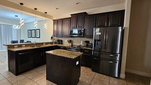 A modern kitchen with dark cabinetry, stainless steel appliances, and a granite countertop island. - Spacious & Cozy Home-Near all Disney Parks (Davenport)