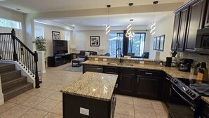 A modern kitchen with granite countertops, dark cabinetry, and stainless steel appliances. - Spacious & Cozy Home-Near all Disney Parks (Davenport)