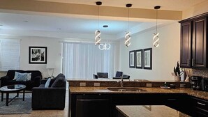 A modern kitchen with a granite countertop, stainless steel appliances, and pendant lighting. - Spacious & Cozy Home-Near all Disney Parks (Davenport)