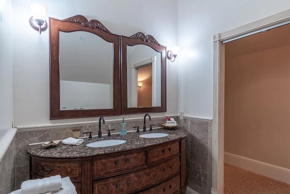 Un baño con tocador doble, dos lavamanos y un espejo grande.