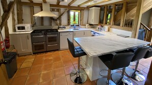 Une cuisine dotée d’un îlot central, d’un four à micro-ondes, d’une cuisinière et d’un lave-linge.