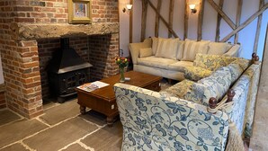 Un salon chaleureux avec une cheminée en briques, un canapé et un fauteuil à motifs.