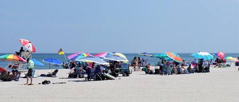 Een strand met kleurrijke parasols en ligbedden.
