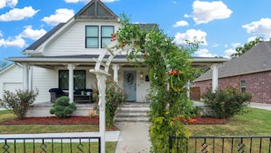 A two-story house with a front porch, a white picket fence, and a brick exterior.