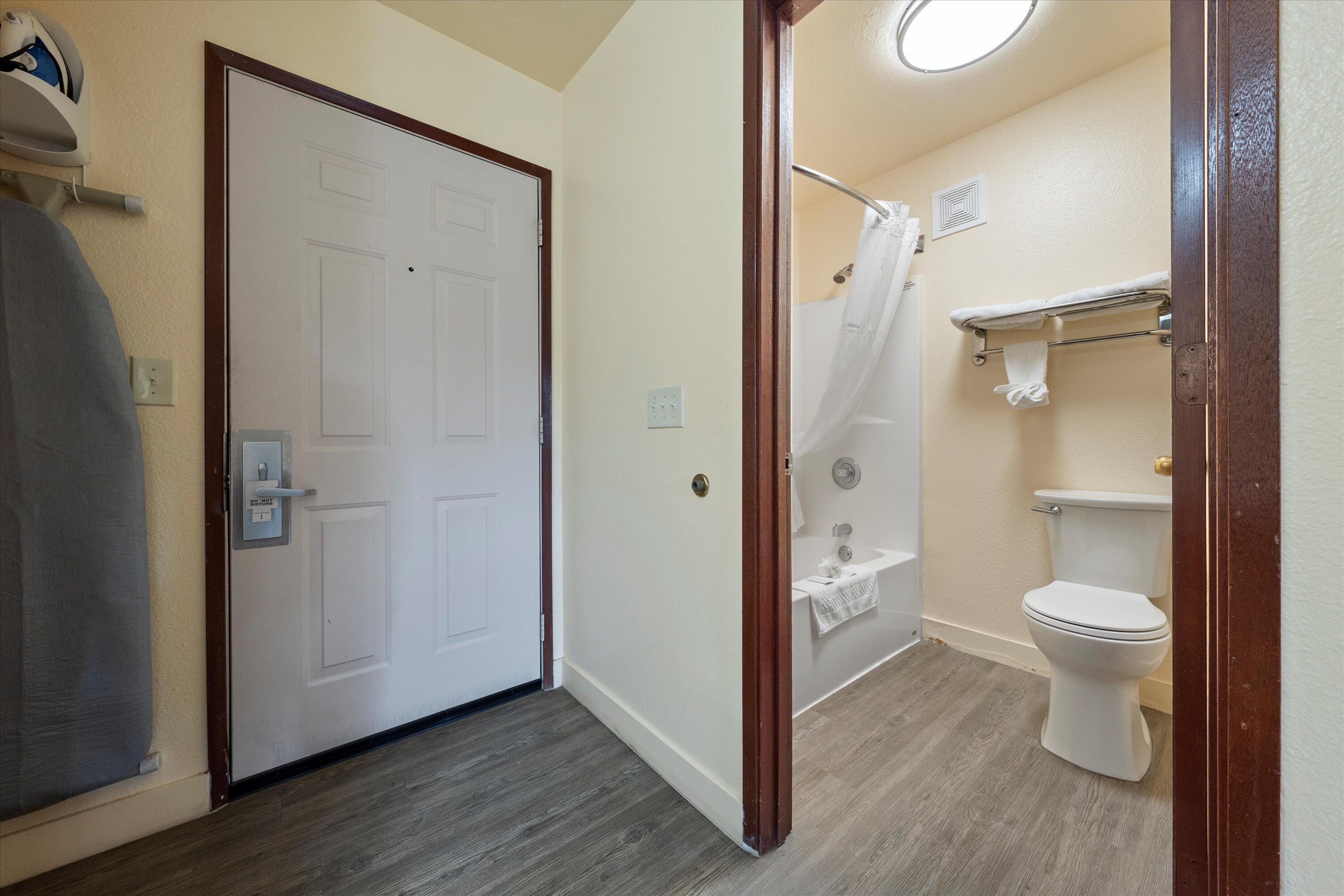 A bathroom with a white toilet, a shower with a curtain, and a towel rack.