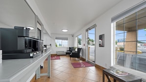 A modern hotel lobby with a kitchenette, seating area, and large windows offering a view of the street. - Quincy INN and Suites (Quincy)