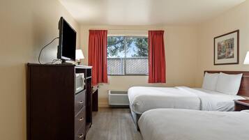 A hotel room with two beds, a TV, a desk, and a window with curtains.