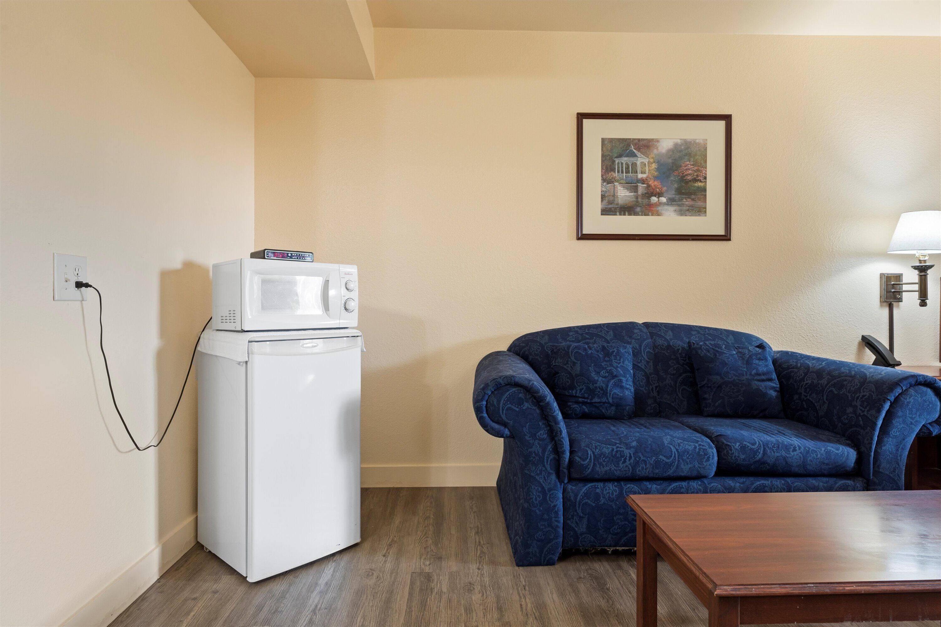 A room with a white appliance, a blue sofa, and a wooden table.