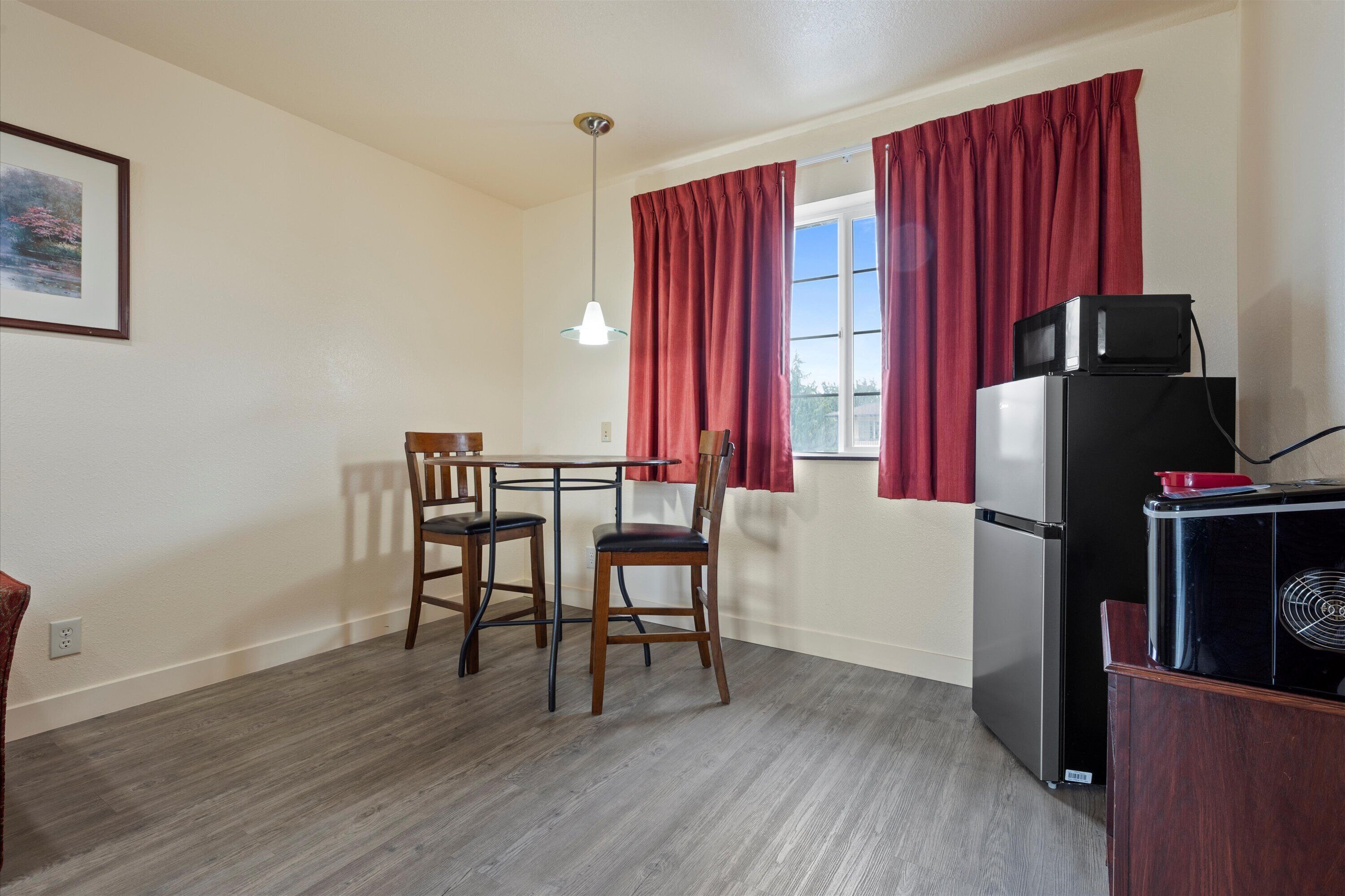 A small kitchen with a dining table and chairs, a refrigerator, and a microwave.
