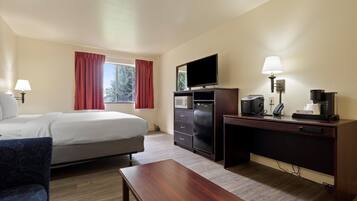 Ein Hotelzimmer mit Bett, Schreibtisch, Fernseher, Kaffeemaschine und Lampe.