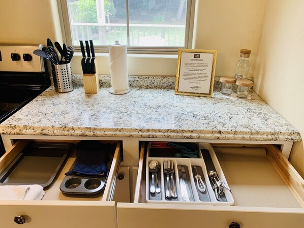A kitchen counter with a granite top, a paper towel holder, a knife block, and a sign with checkout instructions. - Cozy Private Cottage • Near Monterey & Carmel (Salinas)
