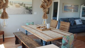 A dining area with a wooden table, benches, and a hanging rope chandelier.