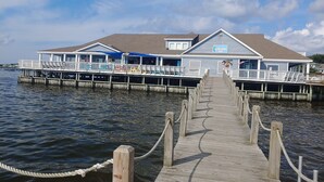 A waterfront property with a wooden dock leading to a building with a sign reading "Waterfront Shops."
