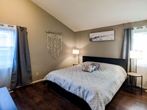 A bedroom with a bed, a wall hanging, a lamp, and a painting.