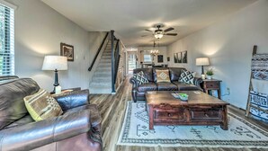 A living room with a leather sofa, a wooden coffee table, and a staircase leading to another level. - Rustic Ruidoso Retreat Near Shops & Mountains! (Ruidoso)