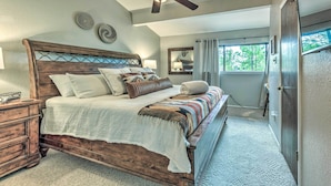 A bedroom with a wooden bed, a ceiling fan, and a view of the outdoors through a window. - Rustic Ruidoso Retreat Near Shops & Mountains! (Ruidoso)