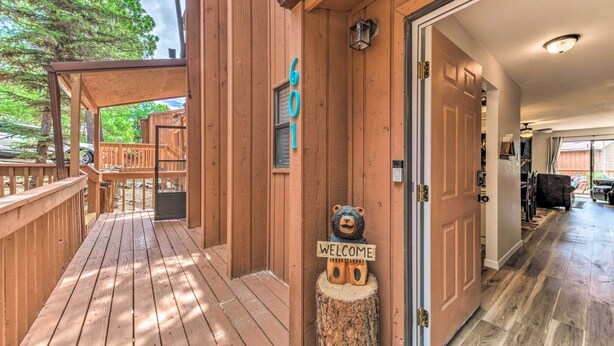 A wooden deck with a 'WELCOME' sign and a bear sculpture, leading to a room with a wooden floor and a door. - Rustic Ruidoso Retreat Near Shops & Mountains! (Ruidoso)
