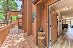 A wooden deck with a 'WELCOME' sign and a bear sculpture, leading to a room with a wooden floor and a door. - Rustic Ruidoso Retreat Near Shops & Mountains! (Ruidoso)