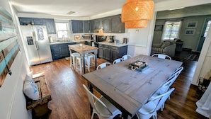 Una cocina moderna con armarios oscuros, una mesa de comedor de madera y una lámpara colgante.