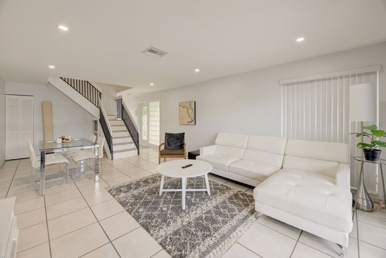 Un salon moderne avec un canapé blanc, une table basse en verre et un escalier.