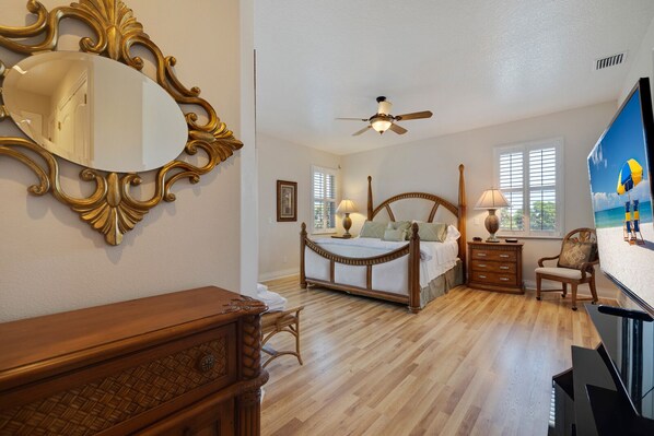 A bedroom with a bed, bedside tables, a dresser, a ceiling fan, and a large mirror.