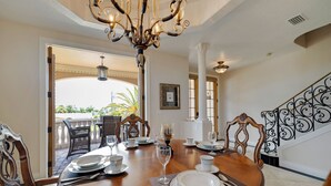 A dining area with a round table set for four, a chandelier, and a view of the outdoor patio.