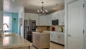 A modern kitchen with white cabinets, stainless steel appliances, and a central island. - O'Keeffe Paints, XL room with lock for Balloon Fiesta! (Rio Rancho)