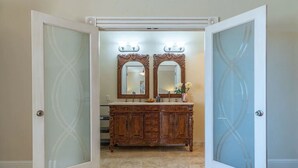 Ein Badezimmer mit einem Holzkonsolenunterschrank, zwei Spiegeln und Milchglasüren.
