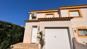 A two-story building with a beige facade, a white door, and a large garage door. - Casa Florence - L'Estartit, Els Salats (Estartit (L´))