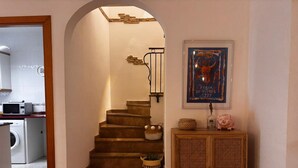 A staircase leading to a second floor, a kitchen area with a washing machine, and a cabinet with decorative items. - Casa Florence - L'Estartit, Els Salats (Estartit (L´))