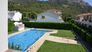 A swimming pool surrounded by well-maintained lawns and buildings, with a mountain in the background. - Casa Florence - L'Estartit, Els Salats (Estartit (L´))