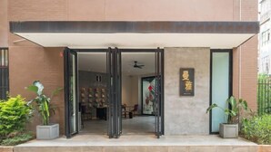 A modern building entrance with a glass door, a ceiling fan, and a sign with Chinese characters. - Manya Hotel (Menghai)