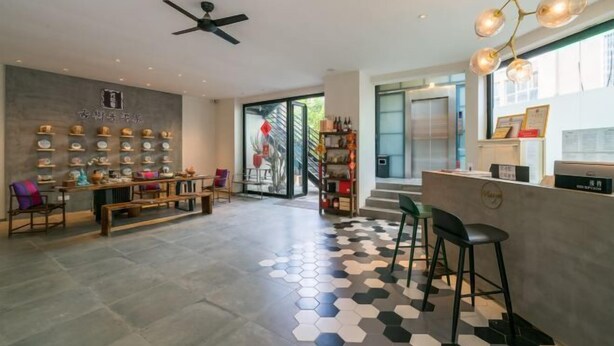 A modern interior with a hexagonal patterned floor, a reception desk, and a ceiling fan. - Manya Hotel (Menghai)