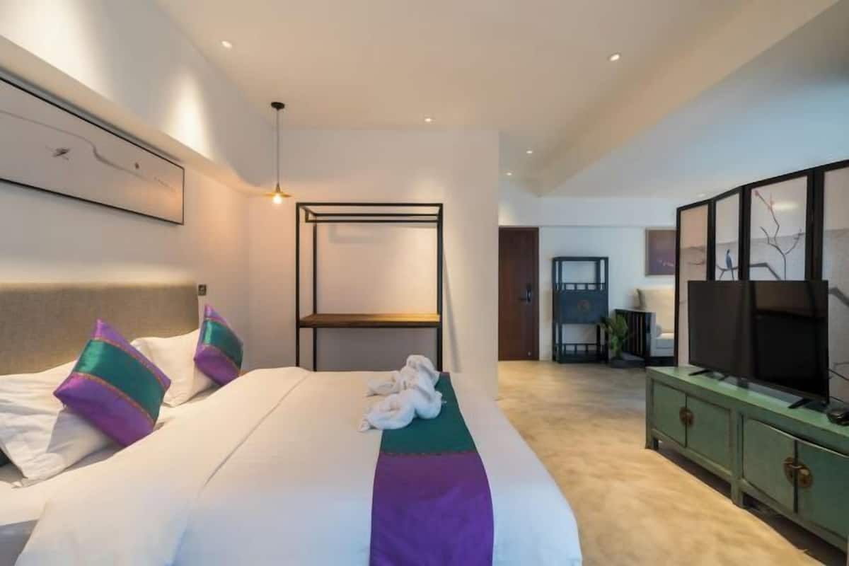 A modern hotel room with a large bed, a television, and a green cabinet.
