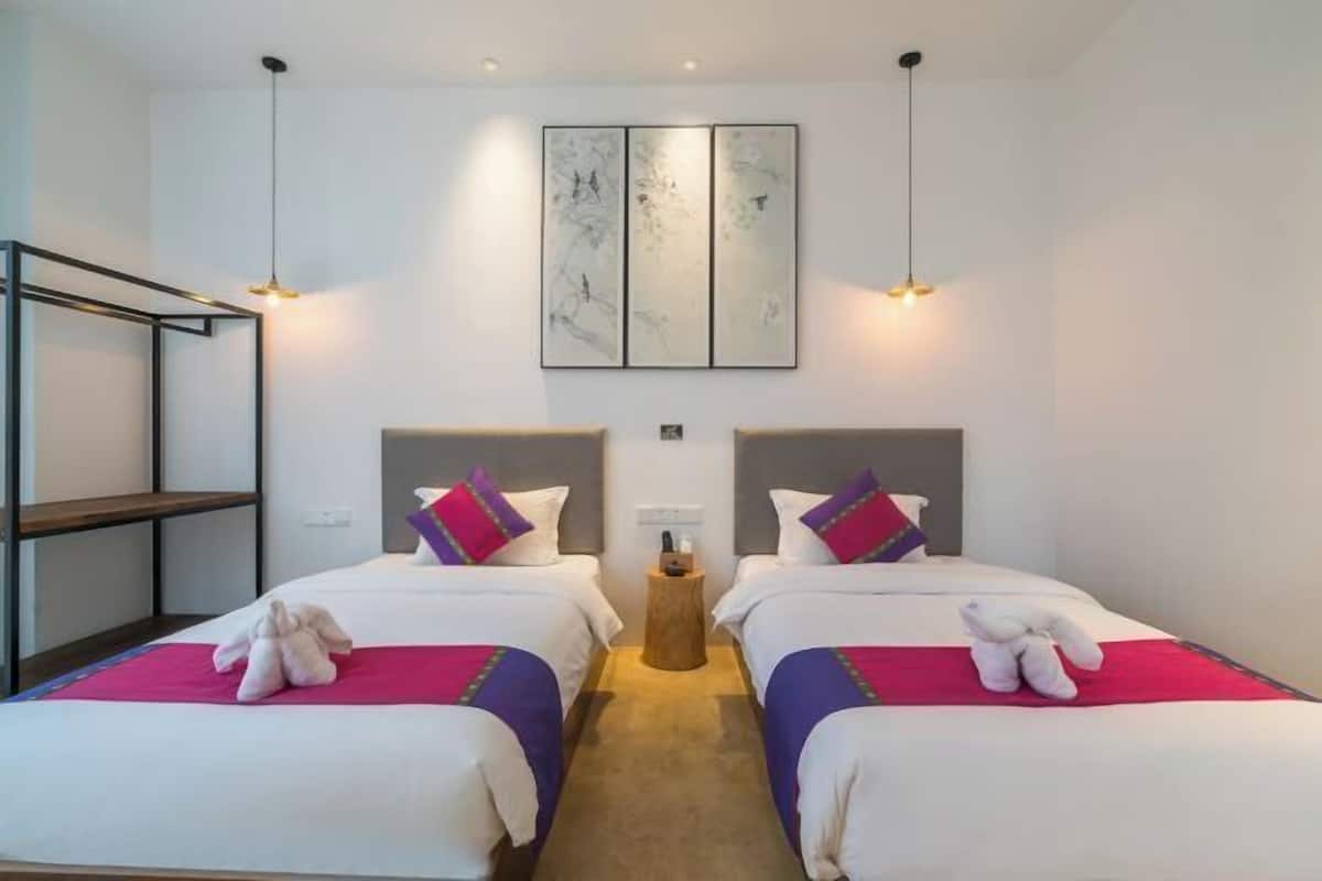 A hotel room with two beds, a wooden side table, and a wall-mounted artwork.