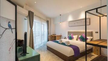 A modern hotel room with a bed, a desk, a chair, a TV, and a window with curtains.
