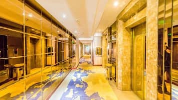 A hotel corridor with mirrored walls, a patterned carpet, and a modern design.