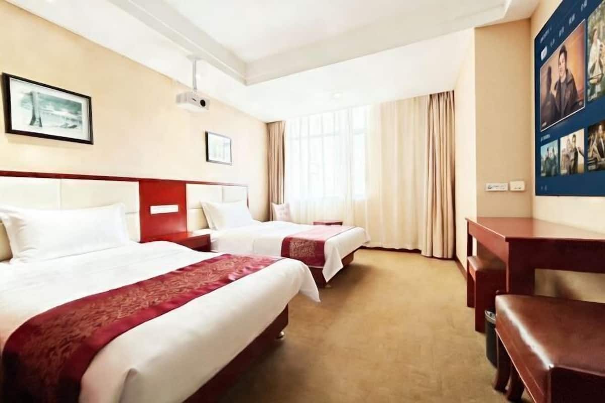 Una habitación de hotel con dos camas, un escritorio y un ventanal con cortinas.