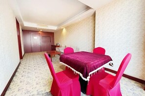 Une chambre d’hôtel comprenant un coin repas avec une table et des chaises, un lit et une porte donnant sur une autre pièce.