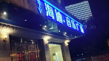 Ein Gebäude mit auffälligem, blauem Schild mit chinesischen Schriftzeichen, einem traditionellen Eingang mit aufwendigen Türen und einer modernen Glasfassade.