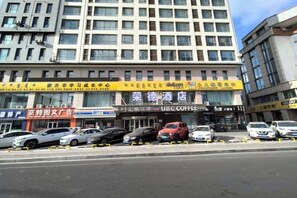 A hotel with multiple floors, a parking lot with several cars, and various storefronts including a coffee shop. - RONGDE (Hohhot Drum Tower, Jiangjun Yashu Metro Station) (Hohhot)