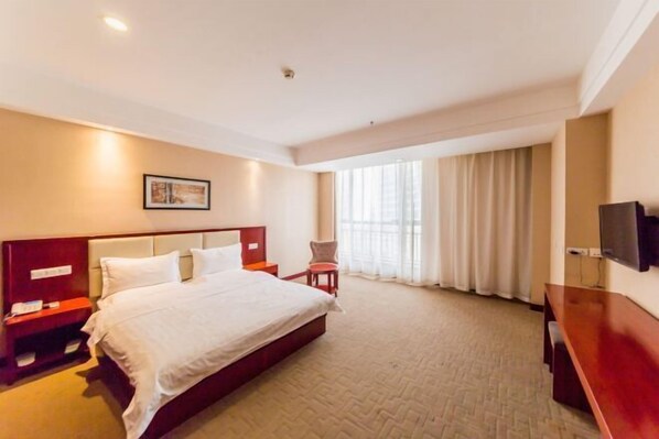 A hotel room with a large bed, a desk, a chair, a TV, and a window with curtains. - RONGDE (Hohhot Drum Tower, Jiangjun Yashu Metro Station) (Hohhot)
