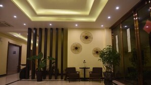 Un vestíbulo con piso pulido, mostrador de recepción, zona de estar y paneles decorativos en la pared.