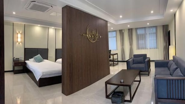Una habitación de hotel moderna con una cama, un sofá, una mesita de centro y una obra de arte colgada en la pared.