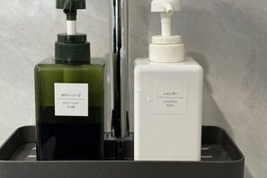 Two bottles of body soap and shampoo in a black tray. - Qi Ting Hotel (Linquan)