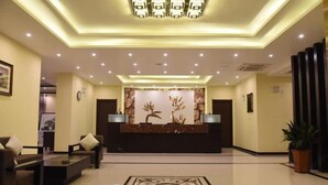 Un vestíbulo de hotel con una recepción, zona de estar y una pared decorativa.