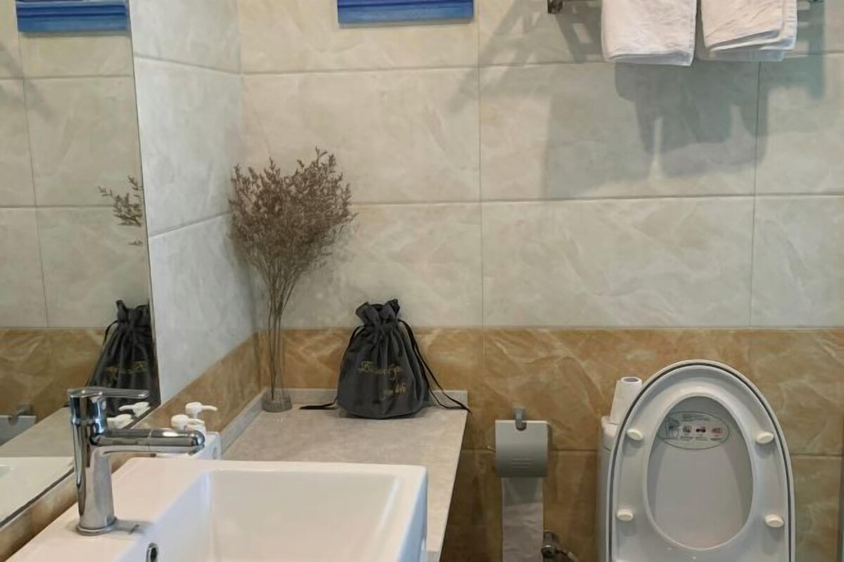 A bathroom with a sink, mirror, toilet, and decorative plants.